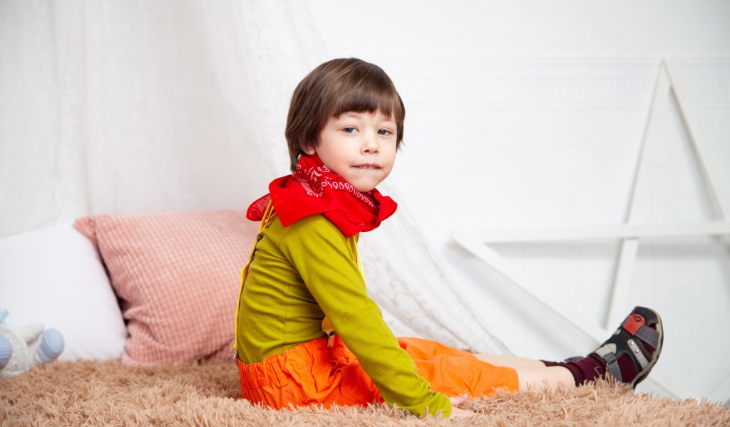 Маленький мальчик сидит на кровати