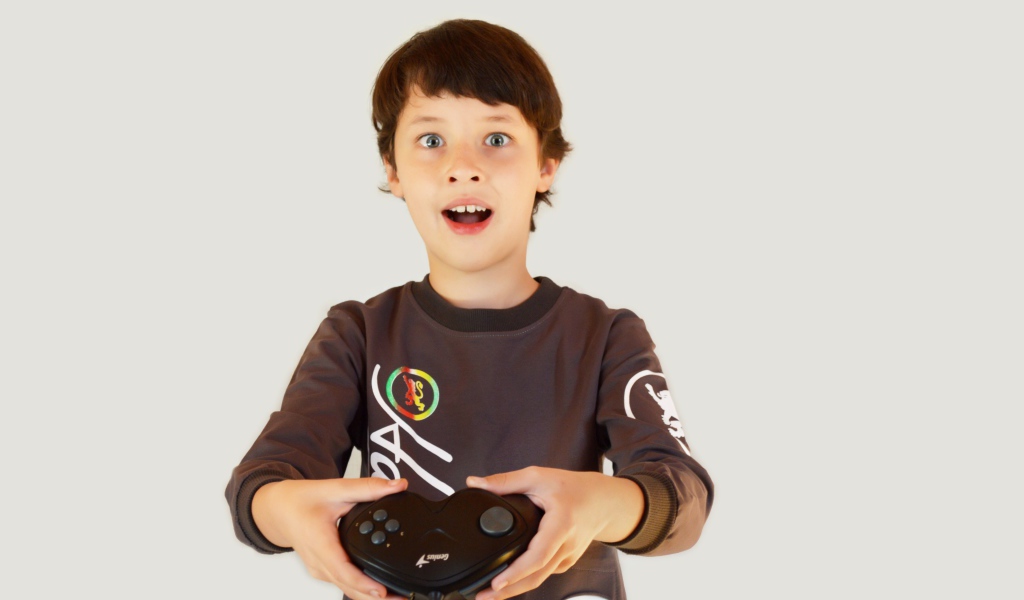 Маленький мальчик с приставкой на сером фоне 