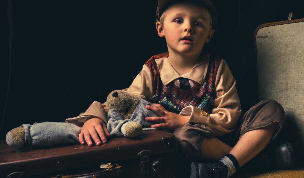 Маленький мальчик с чемоданом и игрушкой