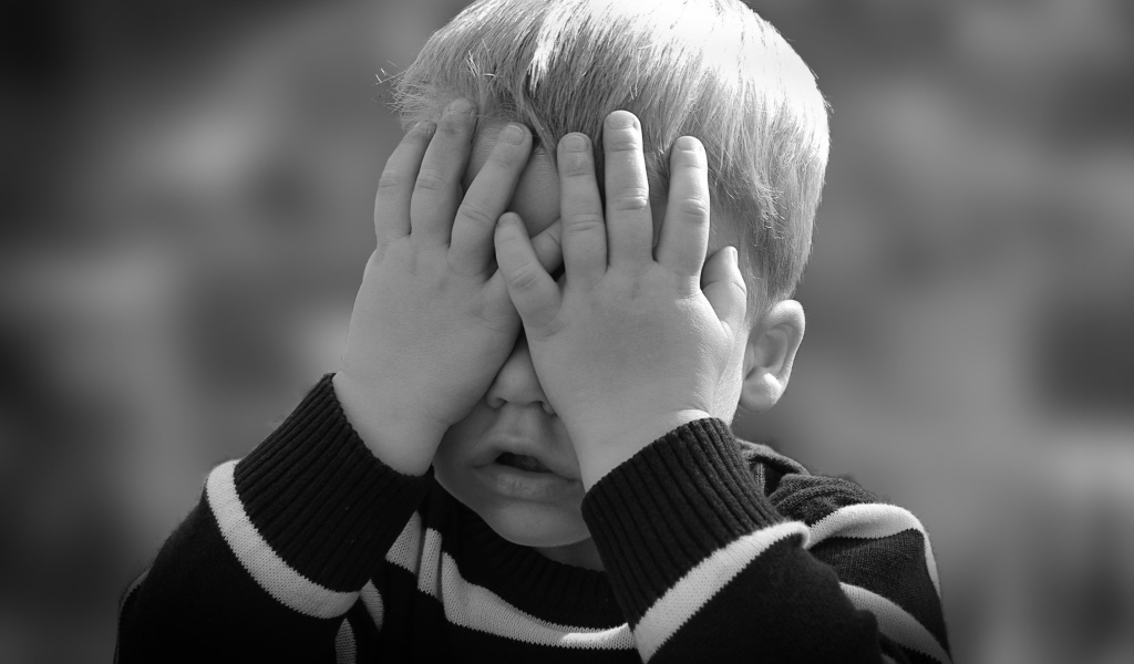 Маленький ребенок закрыл глаза руками