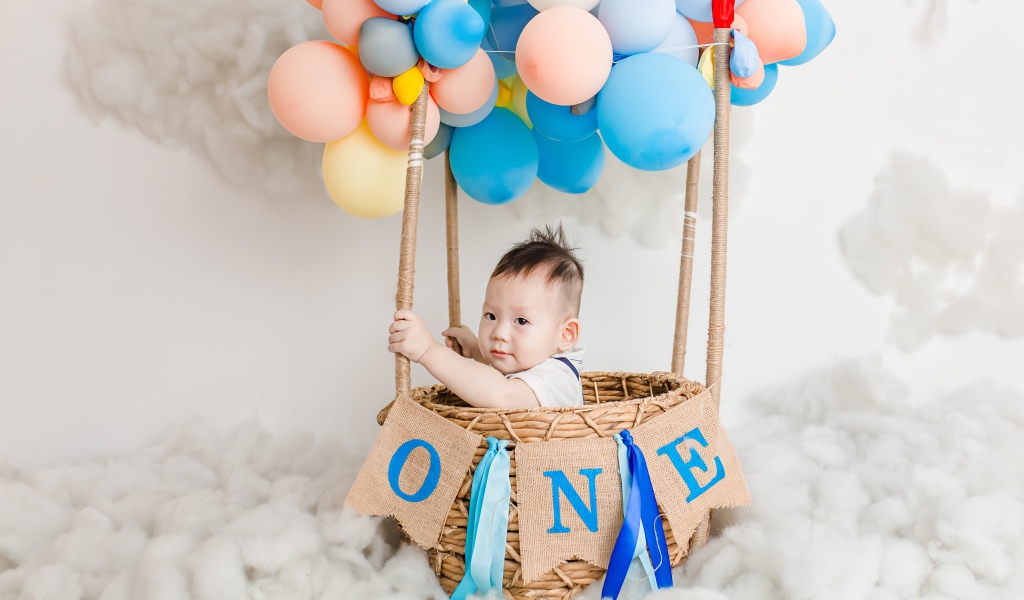 Маленький ребенок в корзине с шариками 