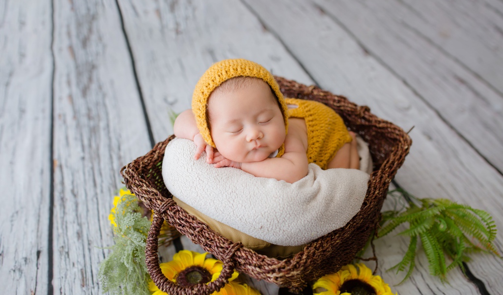 Маленький ребенок спит в плетеной корзине 