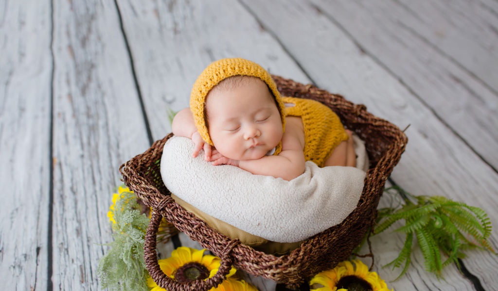 Маленький ребенок спит в плетеной корзине 