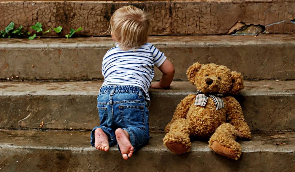 Маленький ребенок с медведем на ступеньках