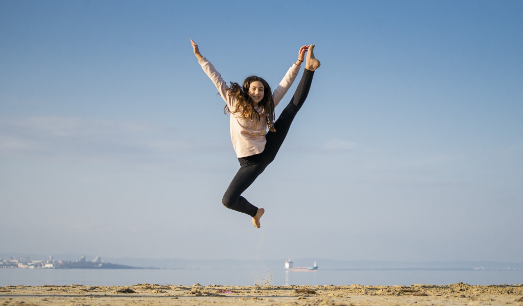 Маленькая девочка гимнастка на песке