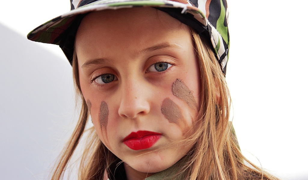 Маленькая девочка в кепке с грязью на лице