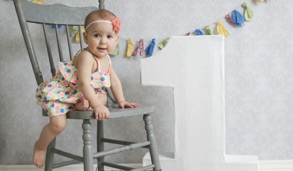 Маленькая девочка в платье на стуле