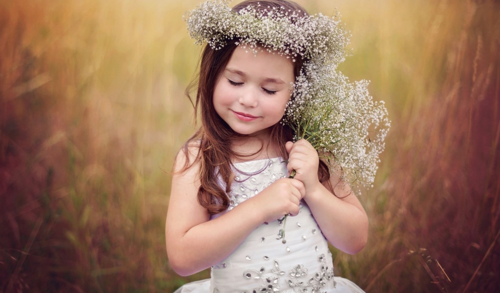 Маленькая девочка в венке с букетом полевых цветов