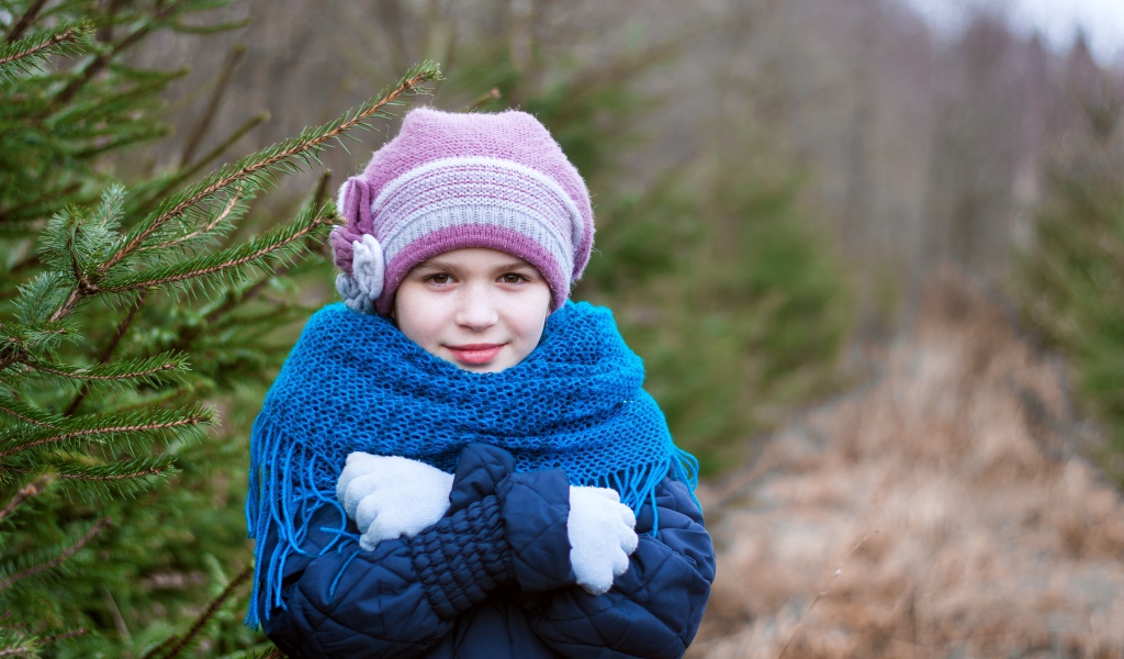 Маленькая девочка в теплой одежде у ели