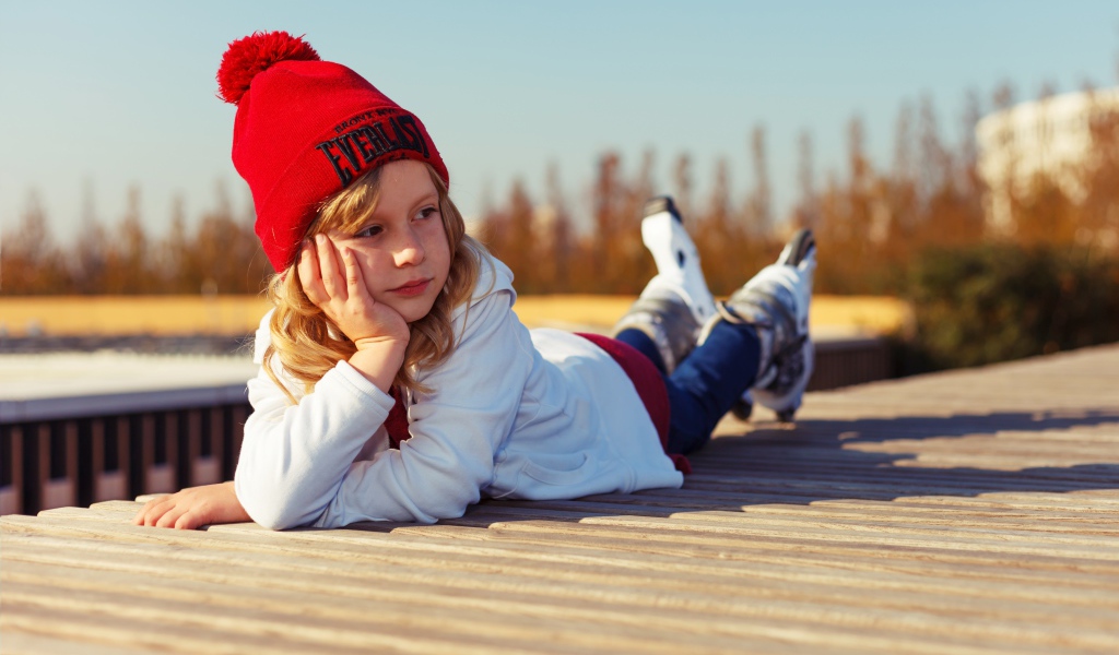 Маленькая девочка лежит на деревянном полу 