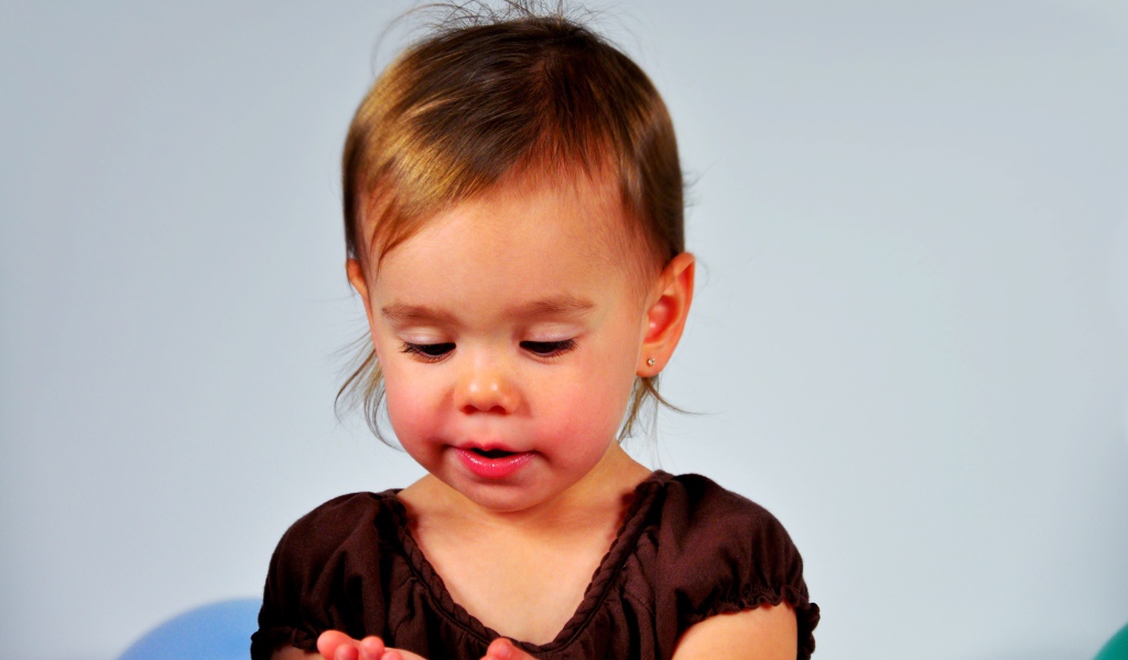 Маленькая девочка смотрит на руки на сером 