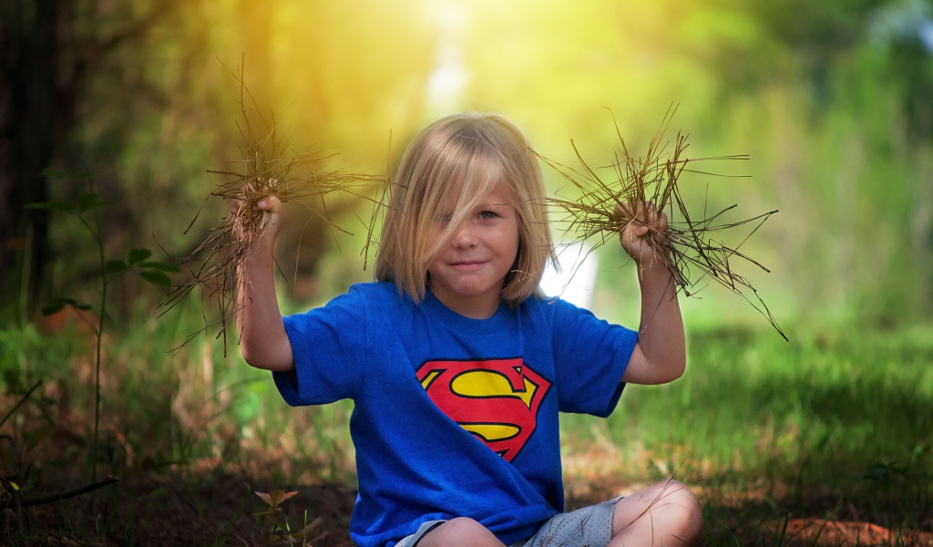 Маленькая девочка сидит на земле с травой