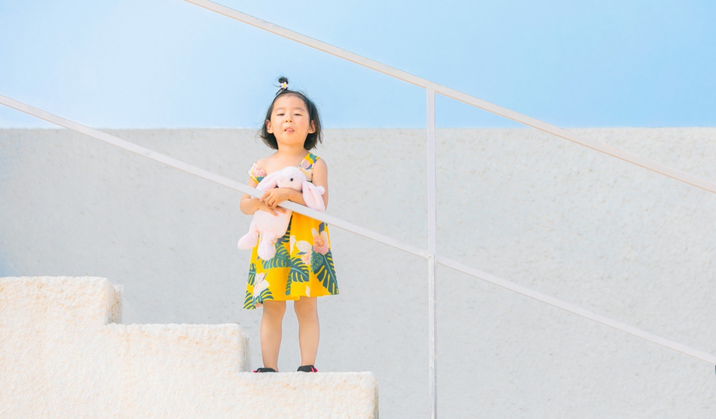 Маленькая девочка с игрушкой на ступеньках 