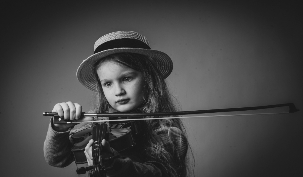 Маленькая девочка со скрипкой в руках на сером фоне