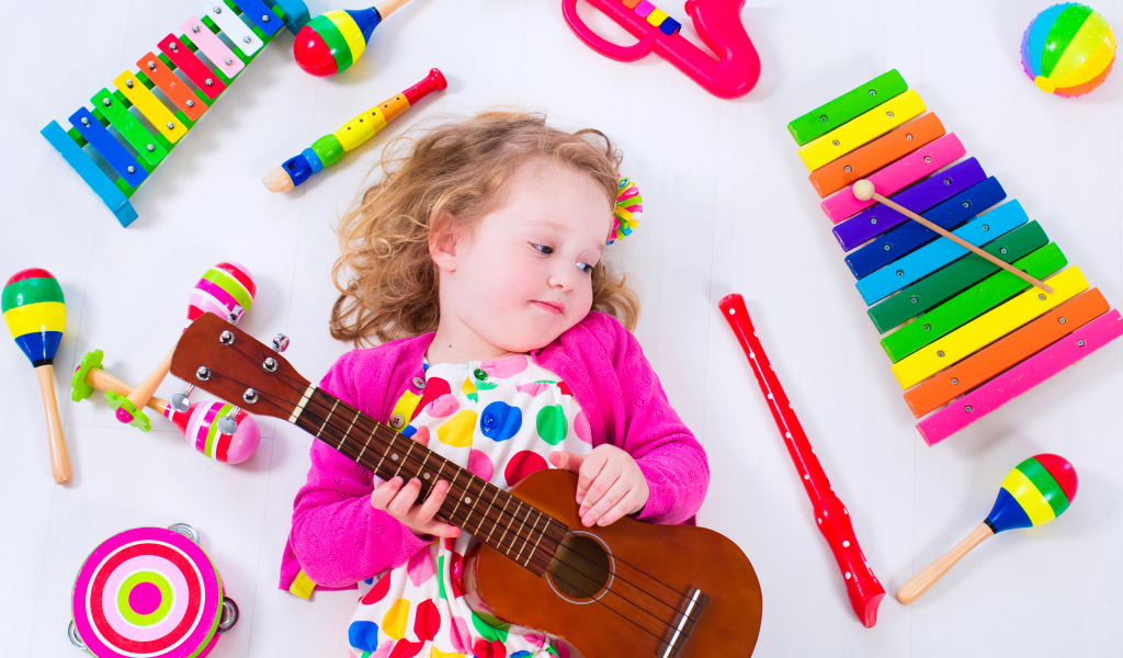 Маленькая девочка с гитарой и игрушечными музыкальными  инструментами 
