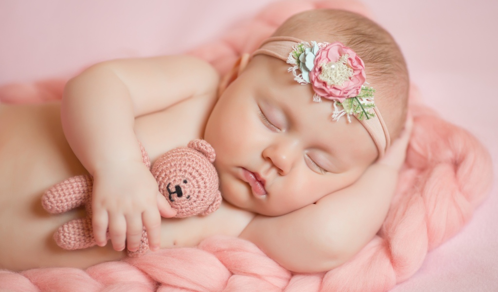 Маленькая новорожденная девочка с вязаным мишкой 