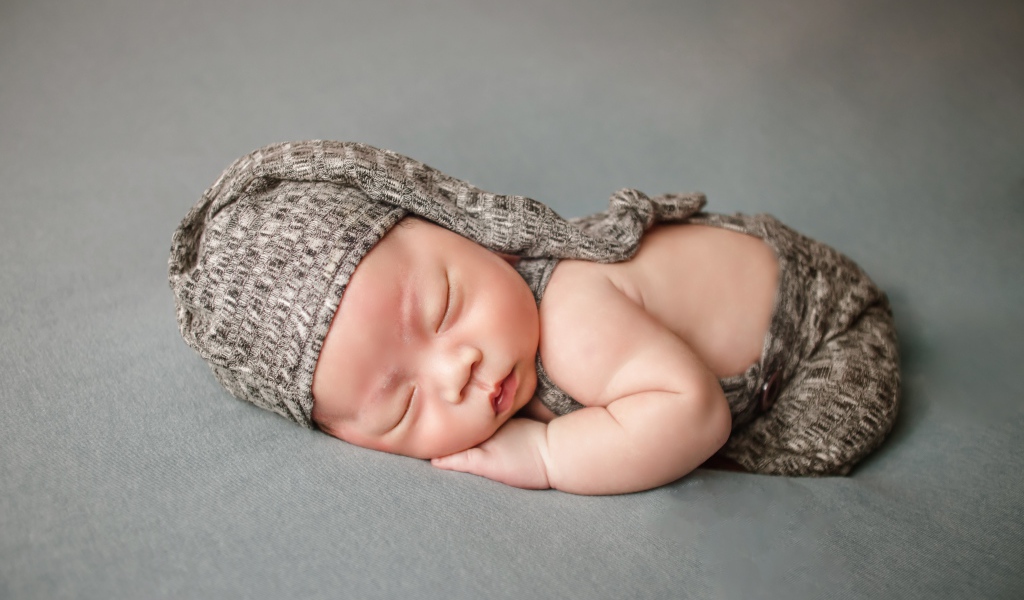 Маленький новорожденный ребенок на сером фоне
