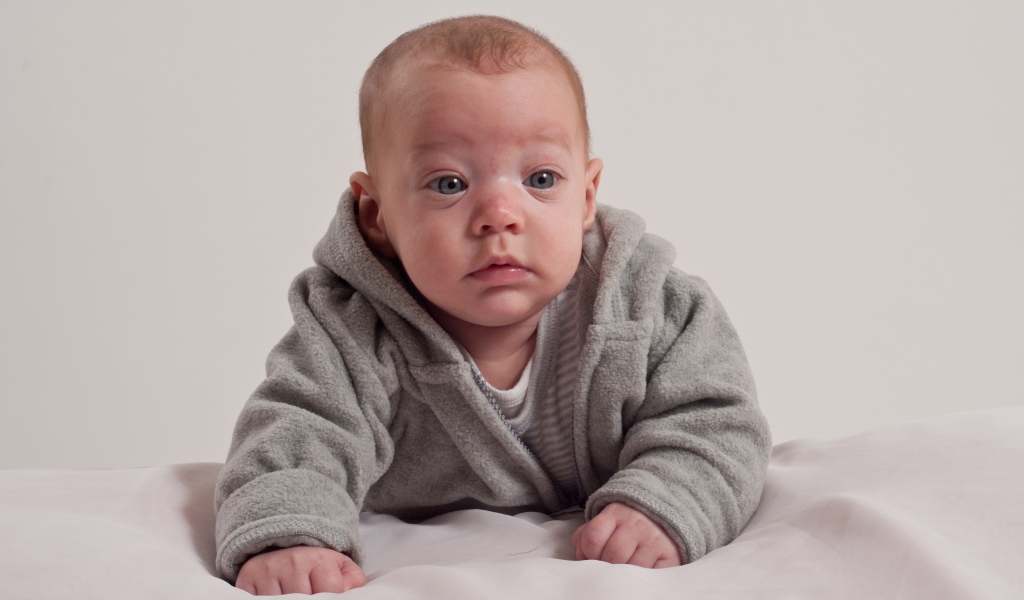 Маленький новорожденный мальчик в сером костюме