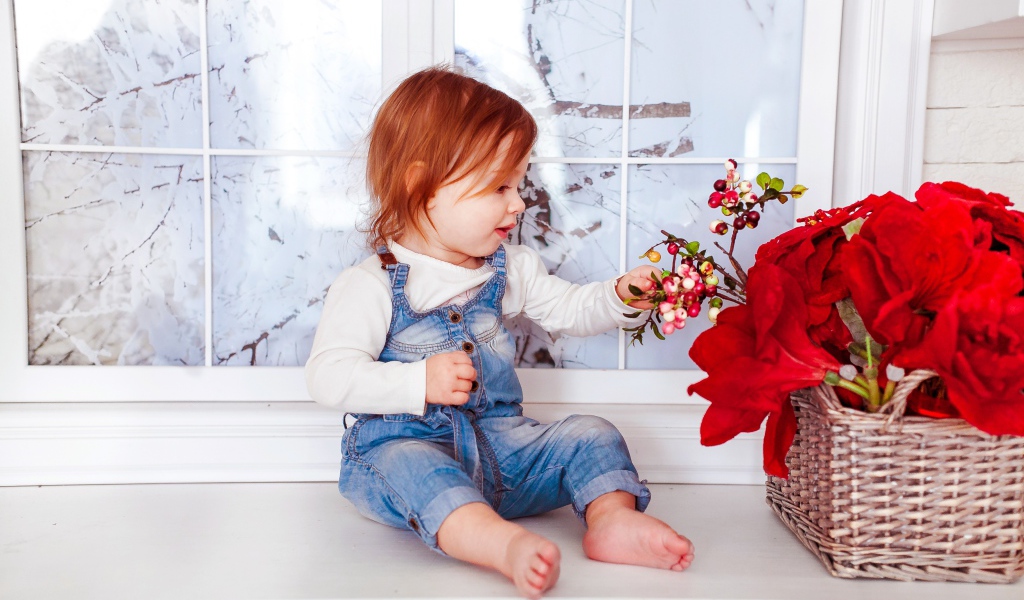 Маленькая рыжеволосая девочка сидит у корзины цветов 