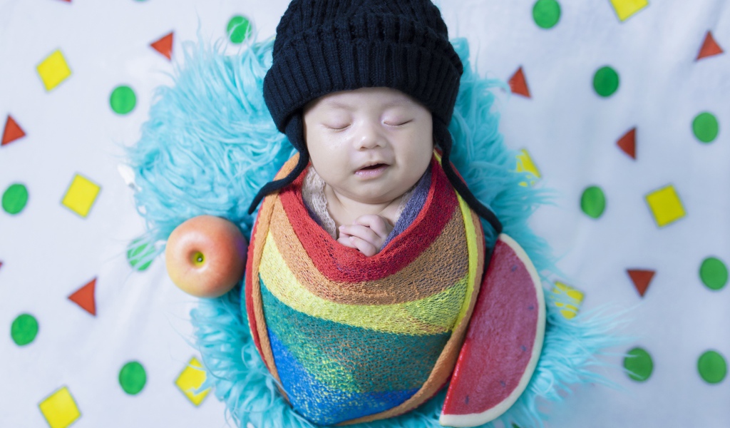 Маленький спящий ребенок в черной шапке 