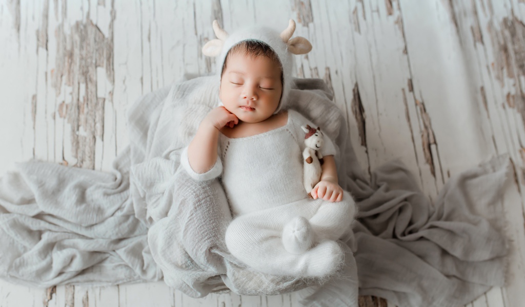 Маленький спящий грудной ребенок в белом костюме