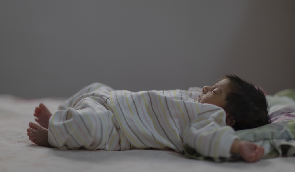 Маленький спящий грудной ребенок на кровати 