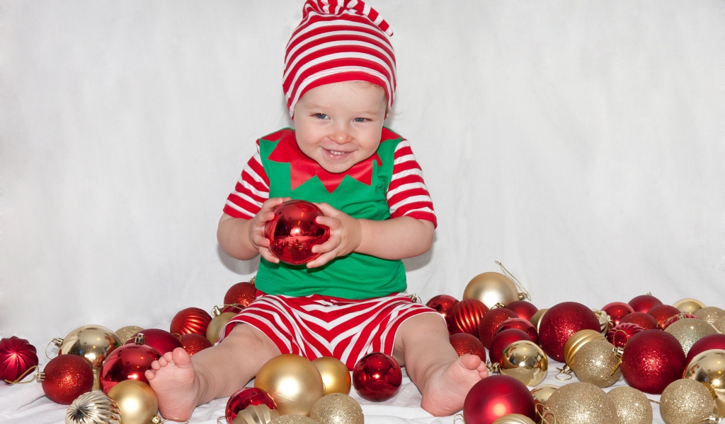 Маленький улыбающийся мальчик с елочными украшениями