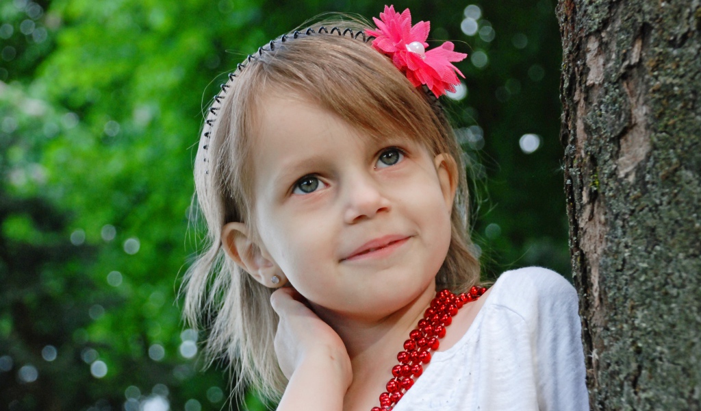 Маленькая улыбающаяся девочка у дерева 