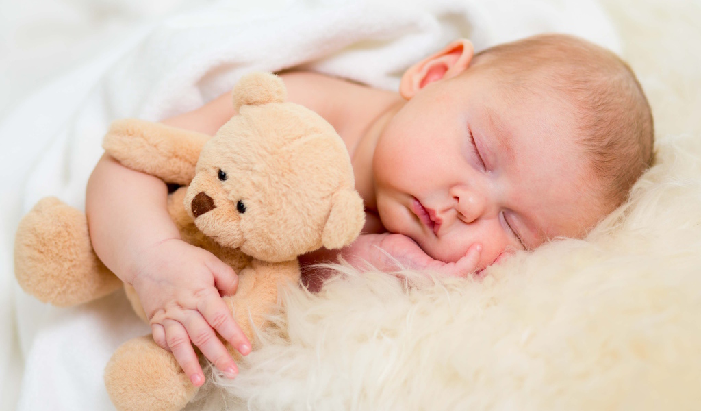 Новорожденный ребенок спит с игрушечным медведем