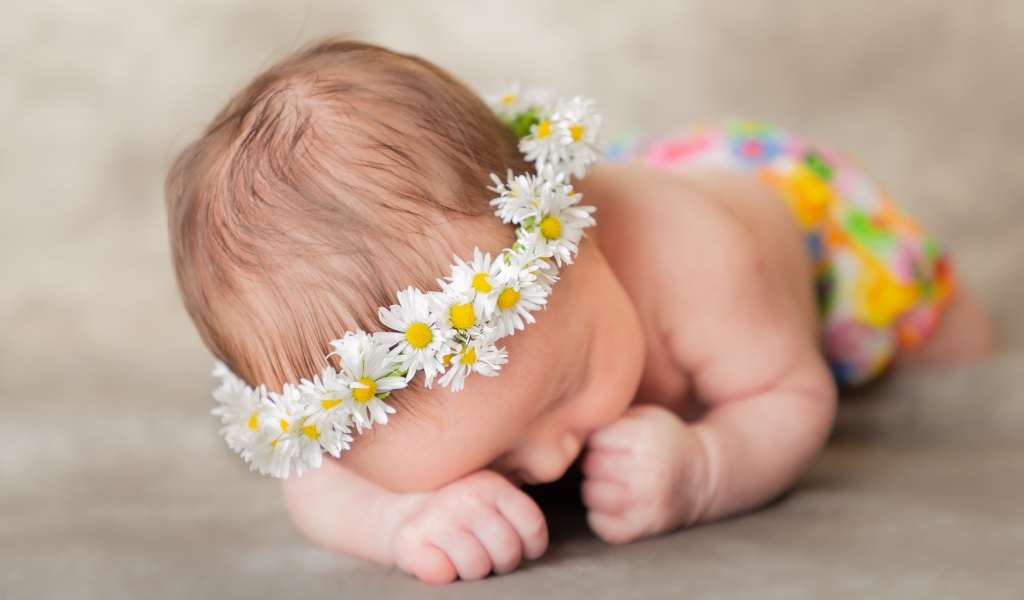 Спящий грудной ребенок в венке из ромашек 