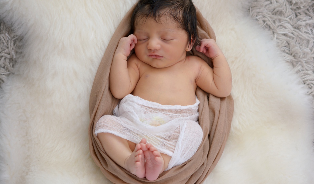 Спящий грудной ребенок на меховом покрывале 