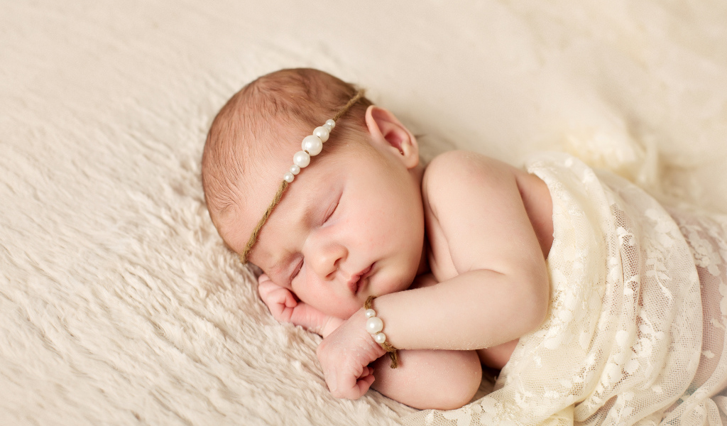 Спящий грудной ребенок с украшением с жемчугом на голове 