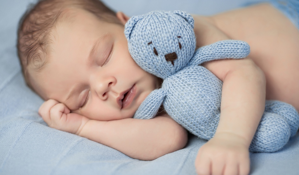 Маленький грудной ребенок с вязаным мишкой