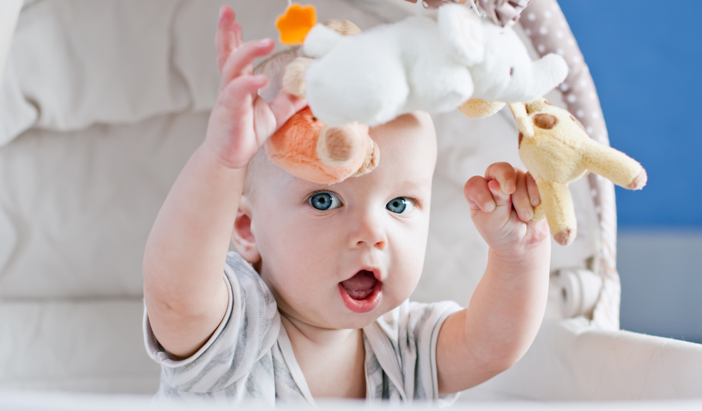 Маленький грудной ребенок в коляске с игрушками 