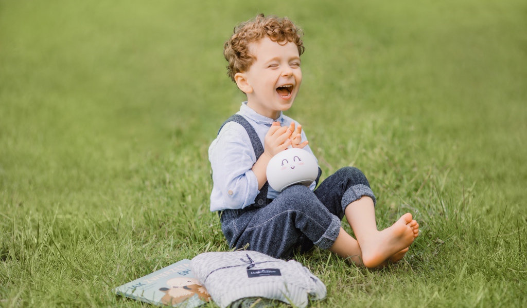 Улыбающийся мальчик сидит на траве