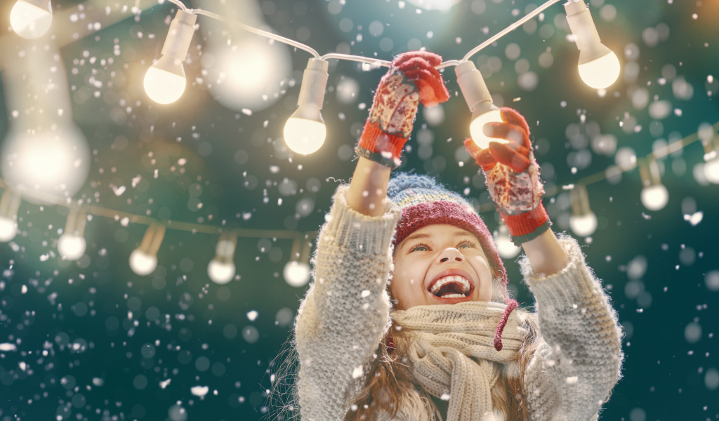 Улыбающаяся девочка вешает лампочки 