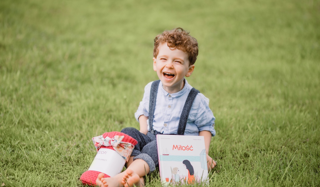 Smiling little boy sitting on green grass