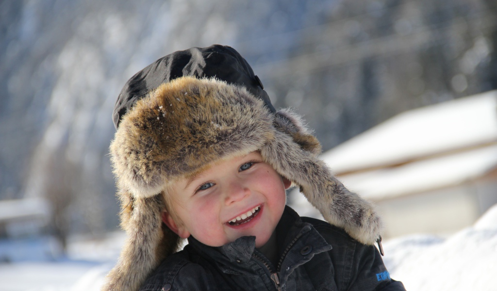 Улыбающийся  маленький мальчик в зимней шапке 