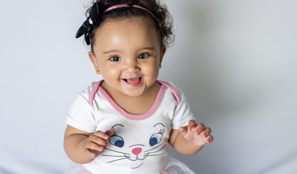 Улыбающаяся маленькая девочка на сером фоне 