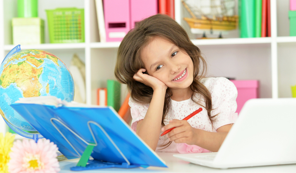 Улыбающаяся девочка ученица делает уроки 