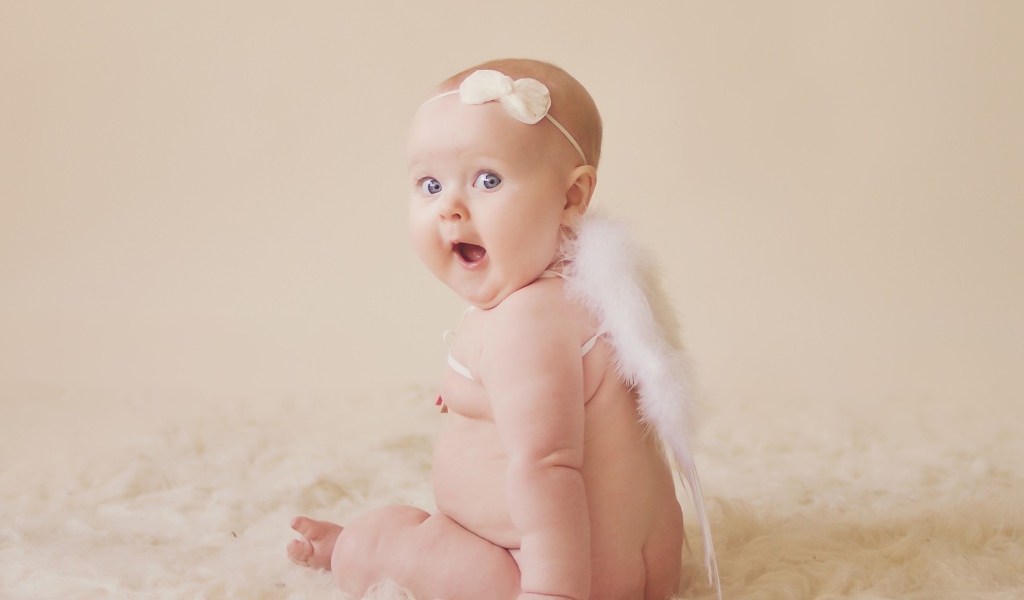 Удивленный грудной ребенок с белыми крыльями за спиной 