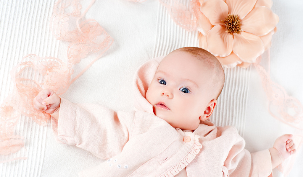 Удивленный новорожденный ребенок с цветком