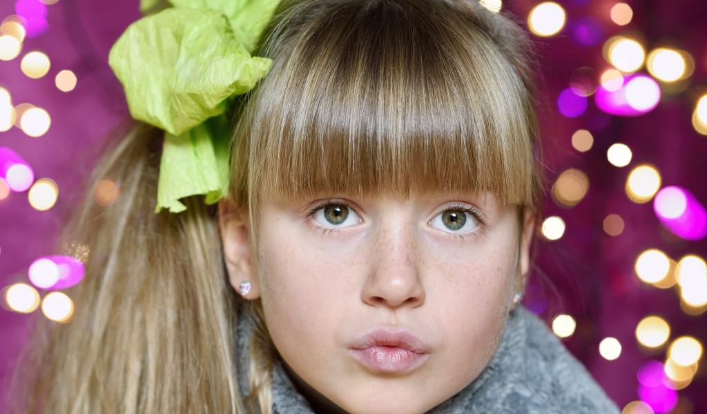 Лицо зеленоглазой девушки с бантом на голове 