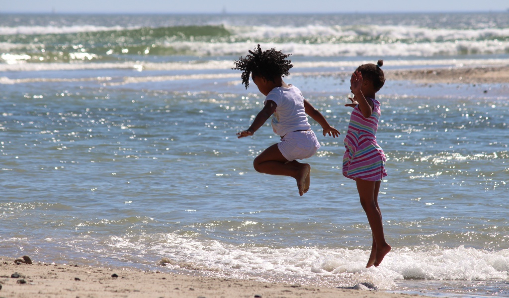 Две маленькие девочки играют на морском берегу