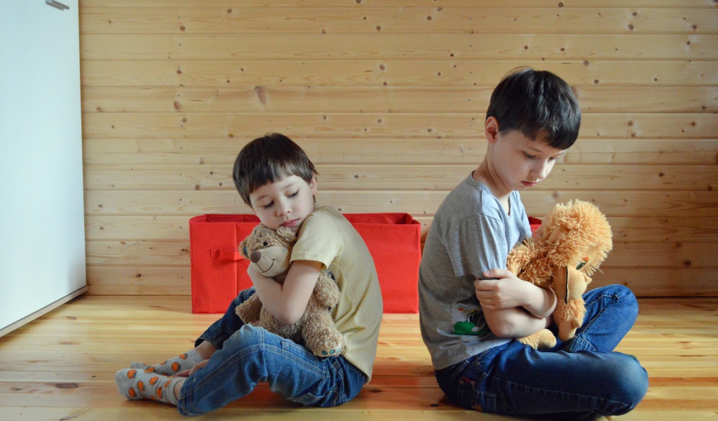 Два маленьких обиженных мальчика сидит на земле