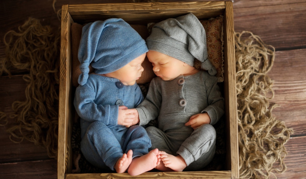 Два маленьких грудных ребенка спят в деревянном ящике