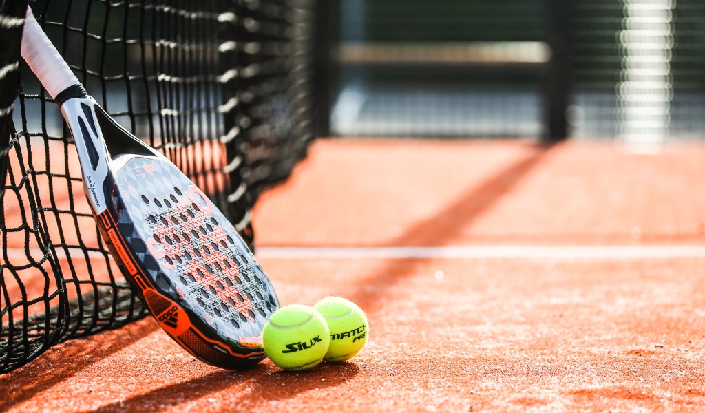 Ракетка и два теннисных мяча у сетки