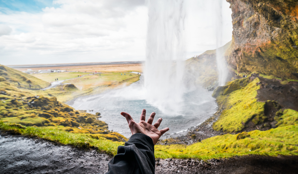 Рука тянется к водопаду Сельяландсфосс, Исландия