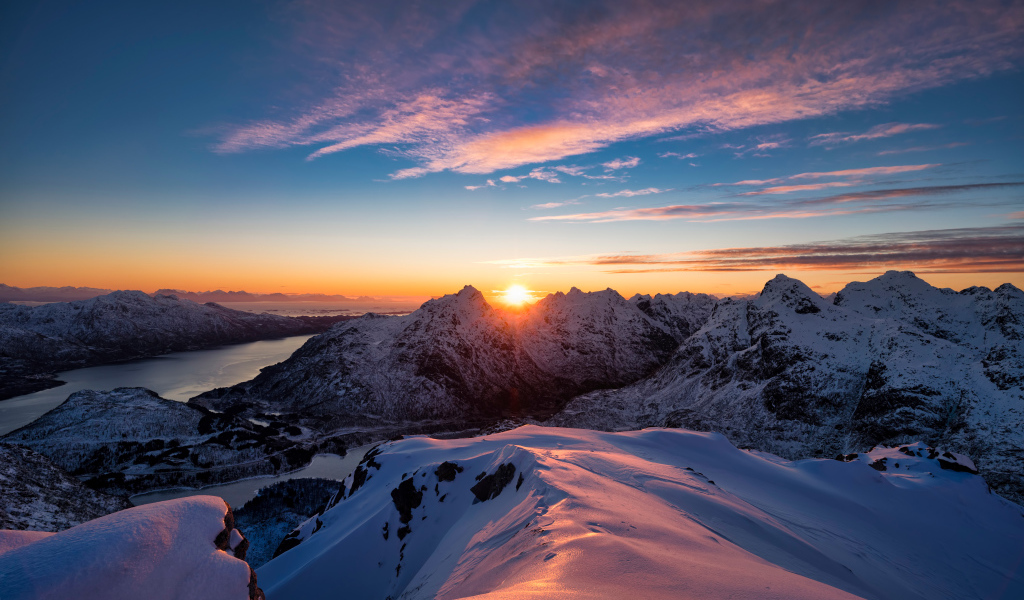 Красивый вид на заснеженные горы в лучах солнца на рассвете, Норвегия