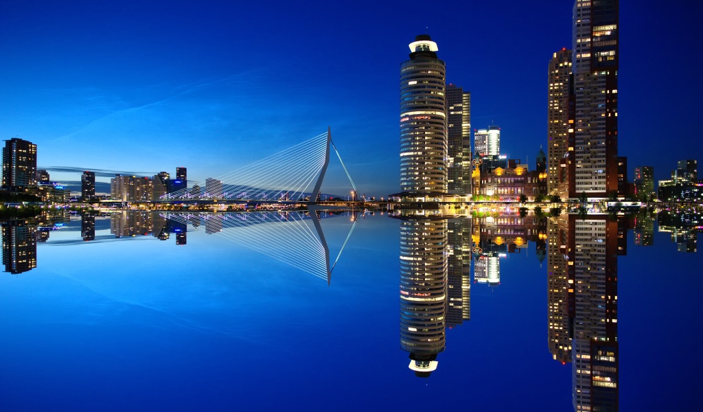 Небоскребы и мост отражаются в тихой воде